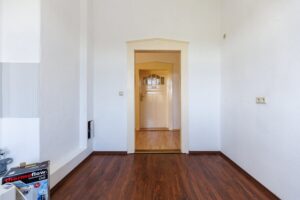 weiße Wände, Fliesenspiegel, brauner Parkettboden, alte beigefarbene Holztür