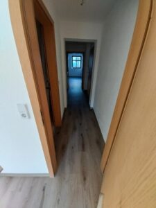 grauer Laminatboden, braune Holztür inkl. Zarge, weiße Wände