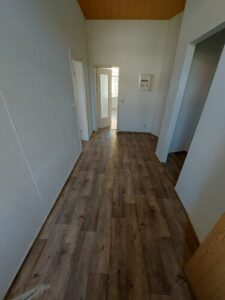 Eingangsbereich: Zugang zum Wohnzimmer und dem Kinderzimmer. Nische, zum abstellen von Gegenständen. brauner Parkettboden. weiße Wände.