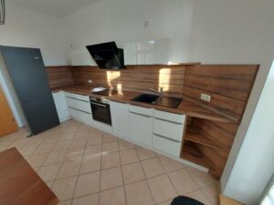 Weiße Einbauküche mit Herd und Backofen, braune Arbeitsplatte