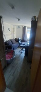 Arbeitszimmer mit dunklen Möbeln, weißen Wänden und holzfarbenen Fußboden