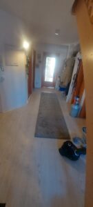 Flur mit weißen Wänden und holzfarbenen Fuußboden