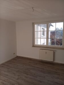 brauner Parkettfußboden, weiße Wände, weißer Heizkörper unter Fenster, weißes Doppelfenster