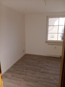 brauner Parkettfußboden, weiße Wände, weißes Fenster