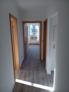 brauner Parkettfußboden, braune Holzzimmertüren, weiße Wände,