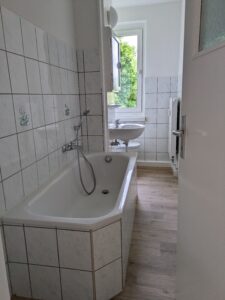 Bad der Wohnung 40877.1.2 in der Schrammstr. 37 in Zittau mit weißen Fliesen und holzfarbenen Fußboden