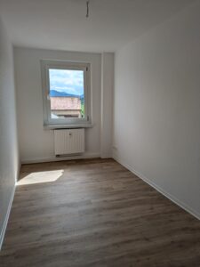 Schlafzimmer mit Weißen Wänden, eichefarbenen Fußboden und einem Fenster