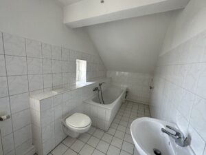 Bad mit Fliesenboden, Badewanne, Waschbecken, Toilette und Fenster
