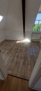 Schlafzimmer mit Laminatboden, Dachrägen und 2 Fenstern.