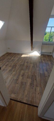 Schlafzimmer mit Laminatboden, Dachrägen und 2 Fenstern.