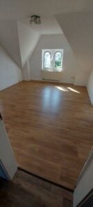 Wohnzimmer mit Laminatboden, Dachrägen und Fenster