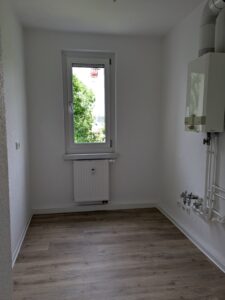 Küche der Wohnung 40877.1.2 in der Schrammstr. 37 in Zittau mit weißen Wänden, einem holzfarbenen Fußboden und einer Therme