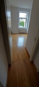 brauner Parkettboden, weiße Wände, weißes Fenster, Heizkörper weiß unter Fenster