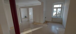 weiße Wände, zwei weiße Fenster, brauner Linoleumbelag