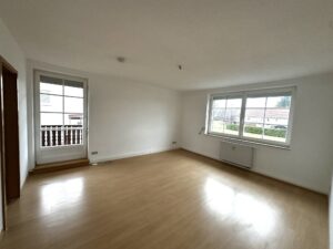 braune Laminat, weiße Wände und weiße Fenster sowie Balkontür