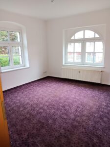 lila Teppichboden, weiße Wände, zwei weiße Fenster mit Rundbogen