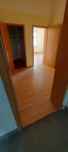 zwei braune Holztüren zum Bad und Wohnzimmer, braune Eingangstür, gelb gestrichene Wände, brauner Laminatfußbodenbelag